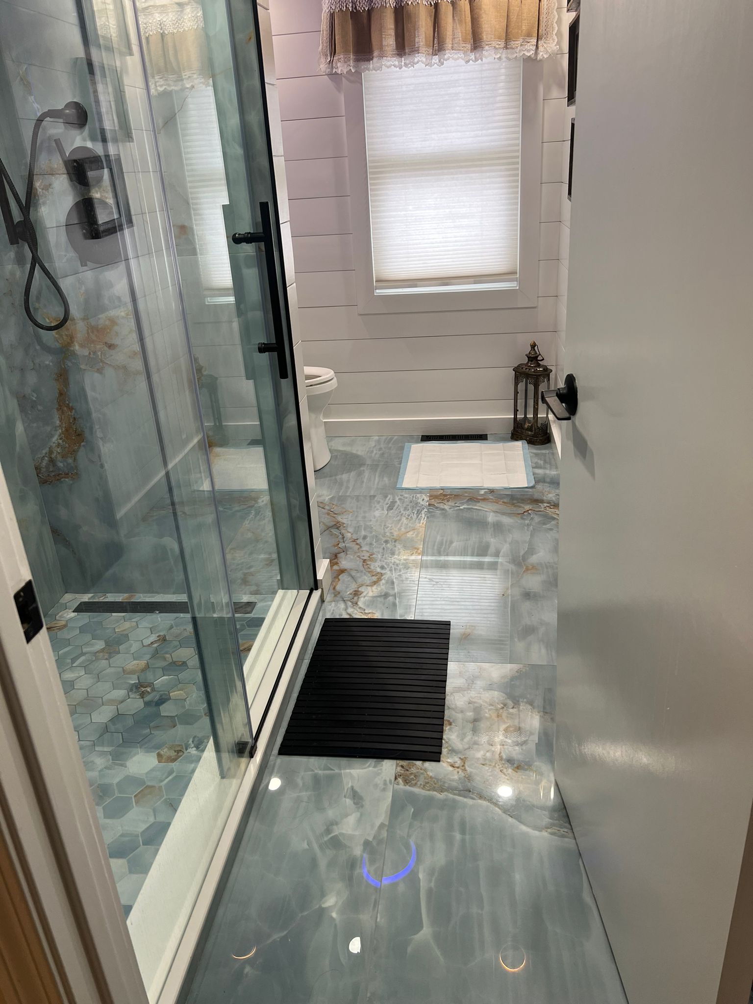 Finished bathroom viewed from the entrance, showing the shower, tile floor and room depth